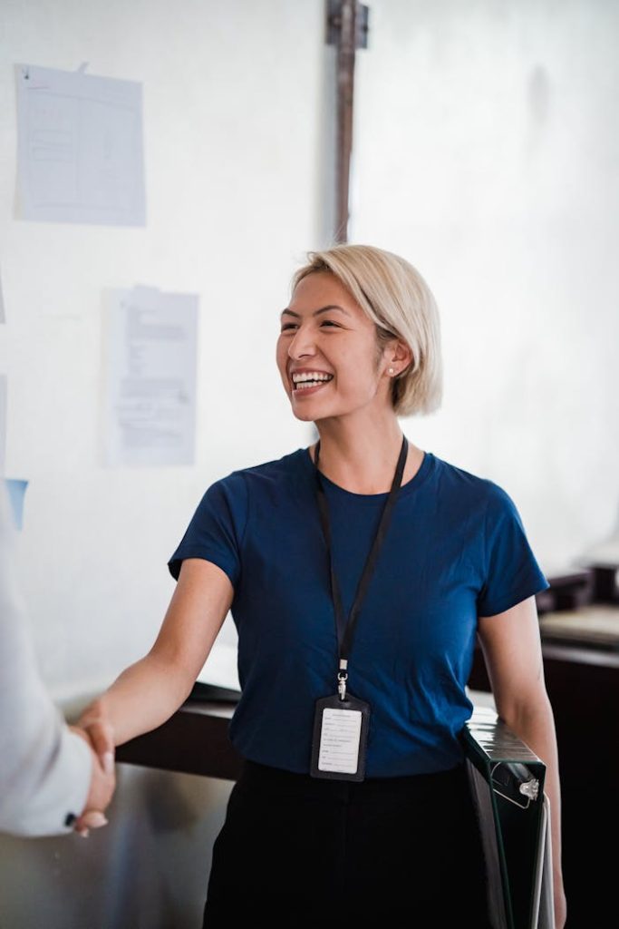 Friendly businesswoman in a blue shirt shaking hands during meeting, radiating professionalism and approachability.